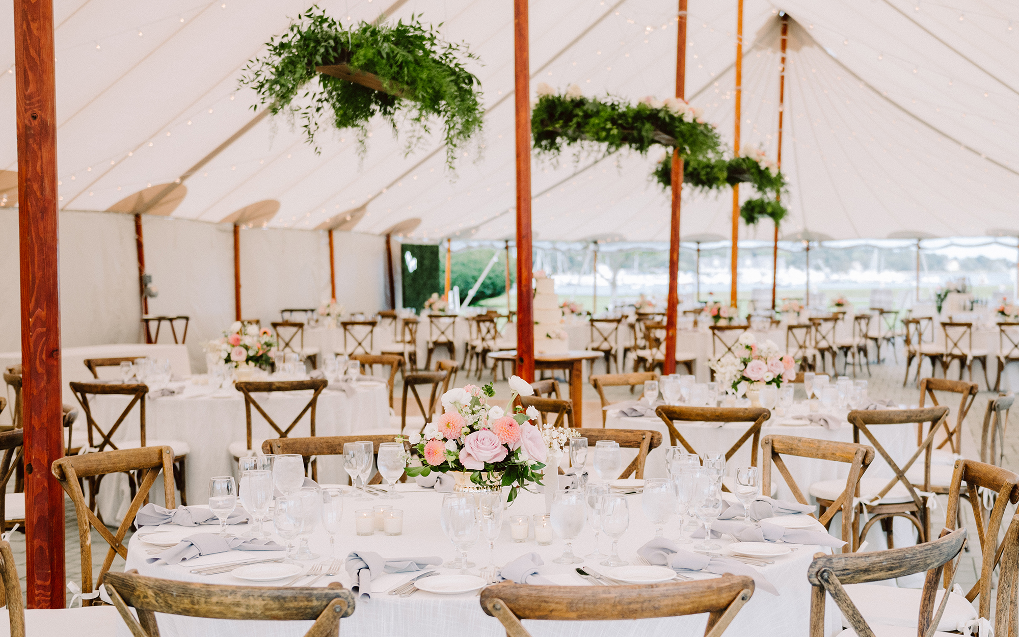 Wedding table settings beneath large outdoor tent