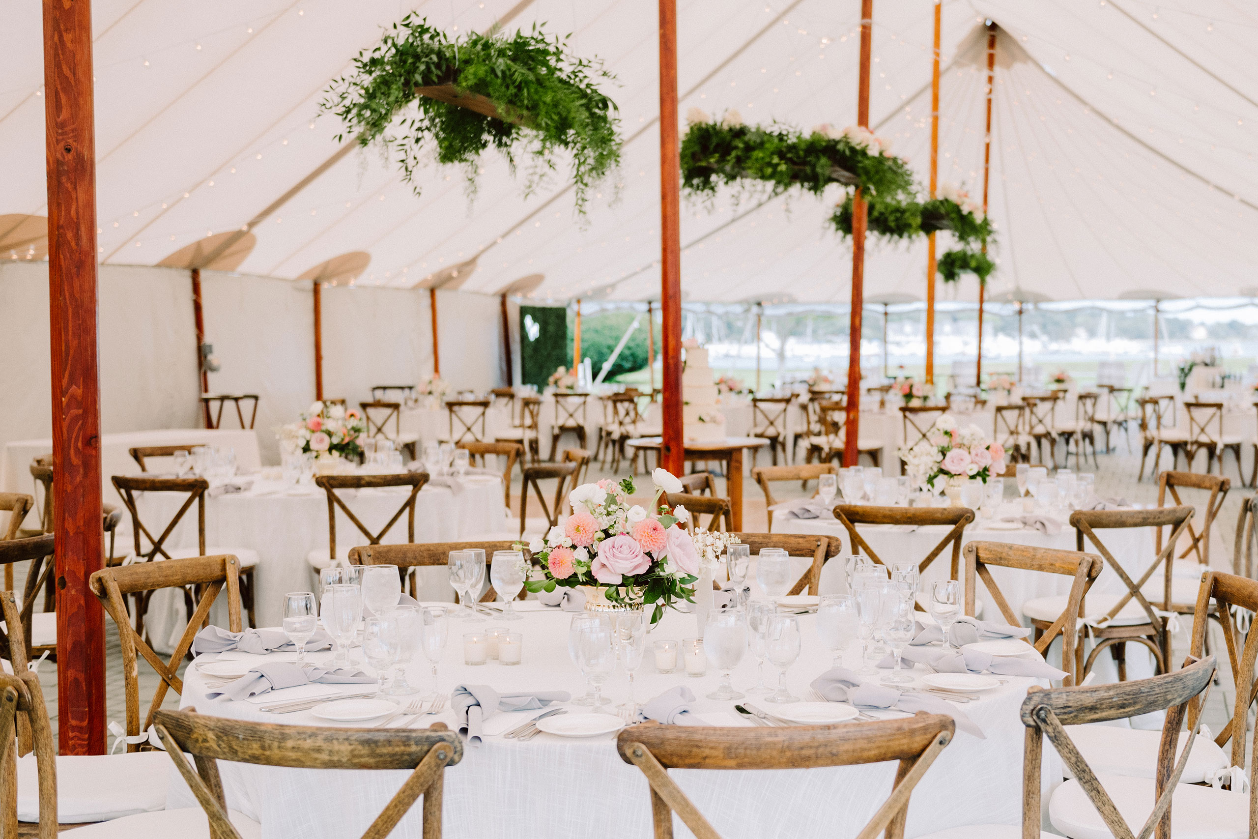 Wedding table settings beneath large outdoor tent