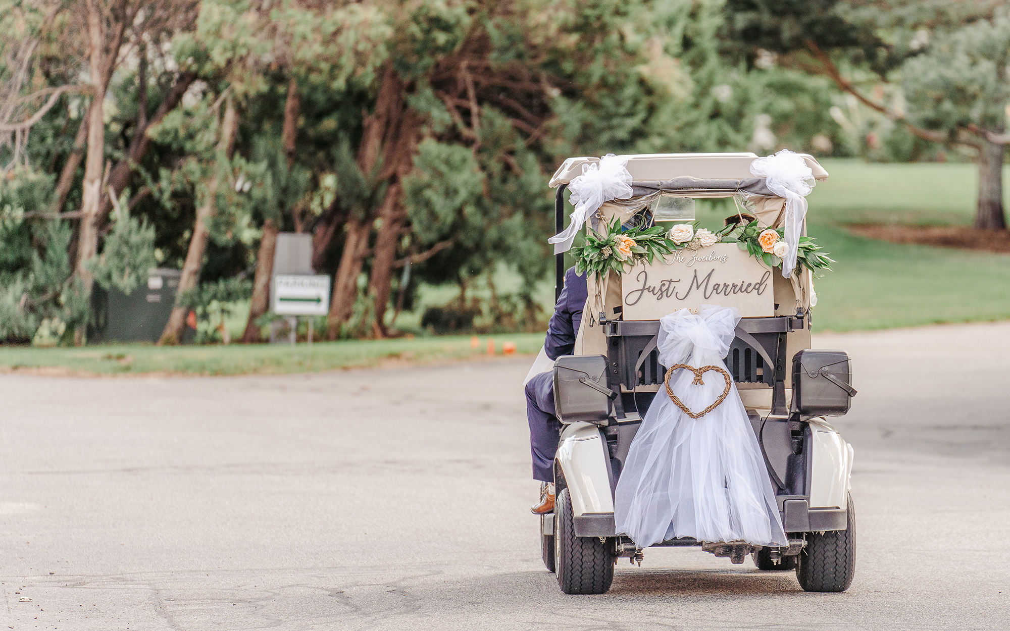 Bride and groom riding in golf cart with Just Married sign on back
