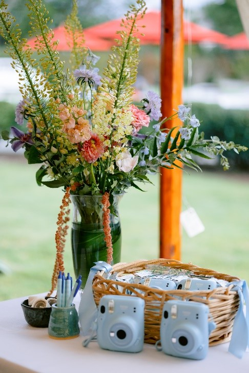 Flowers and a basket of blue polaroid cameras as party favours