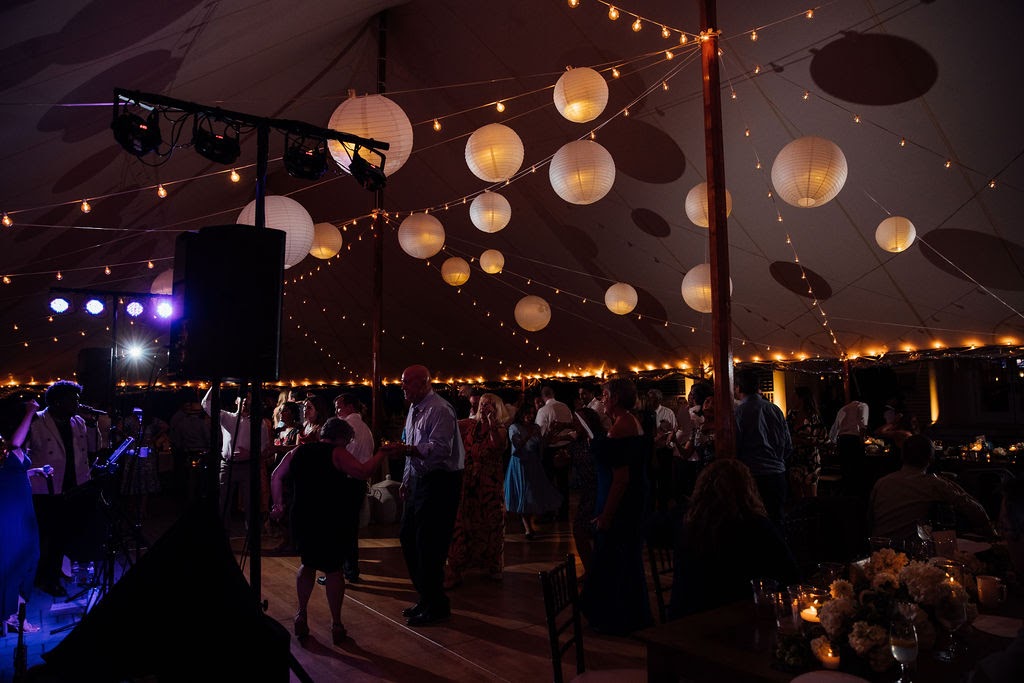a group of people dancing in a tent with lights.