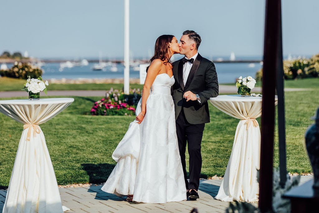 a bride and groom kissing in front of the sea.