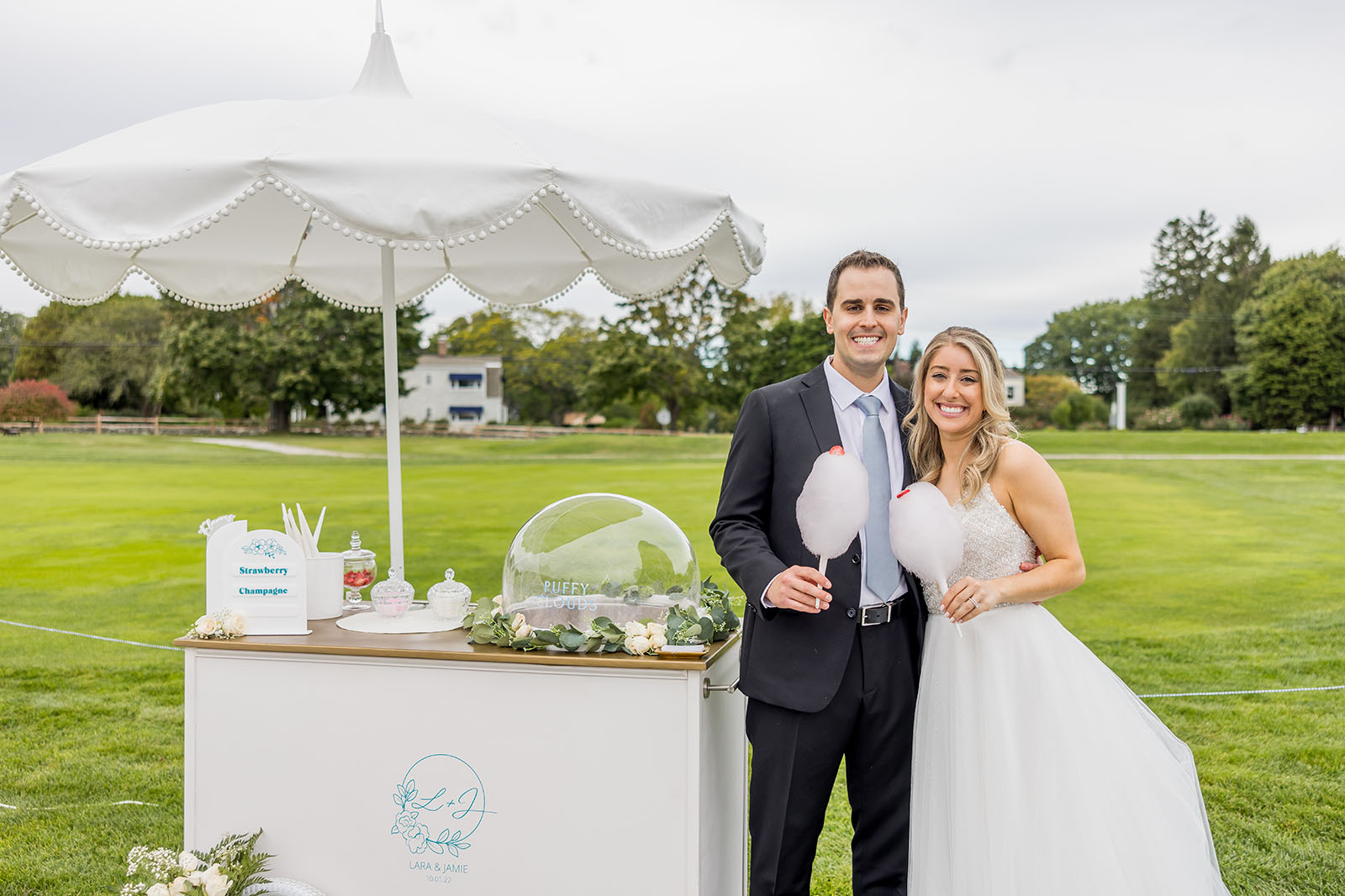 Smiling married couple at wedding posing with cotton candy food cart