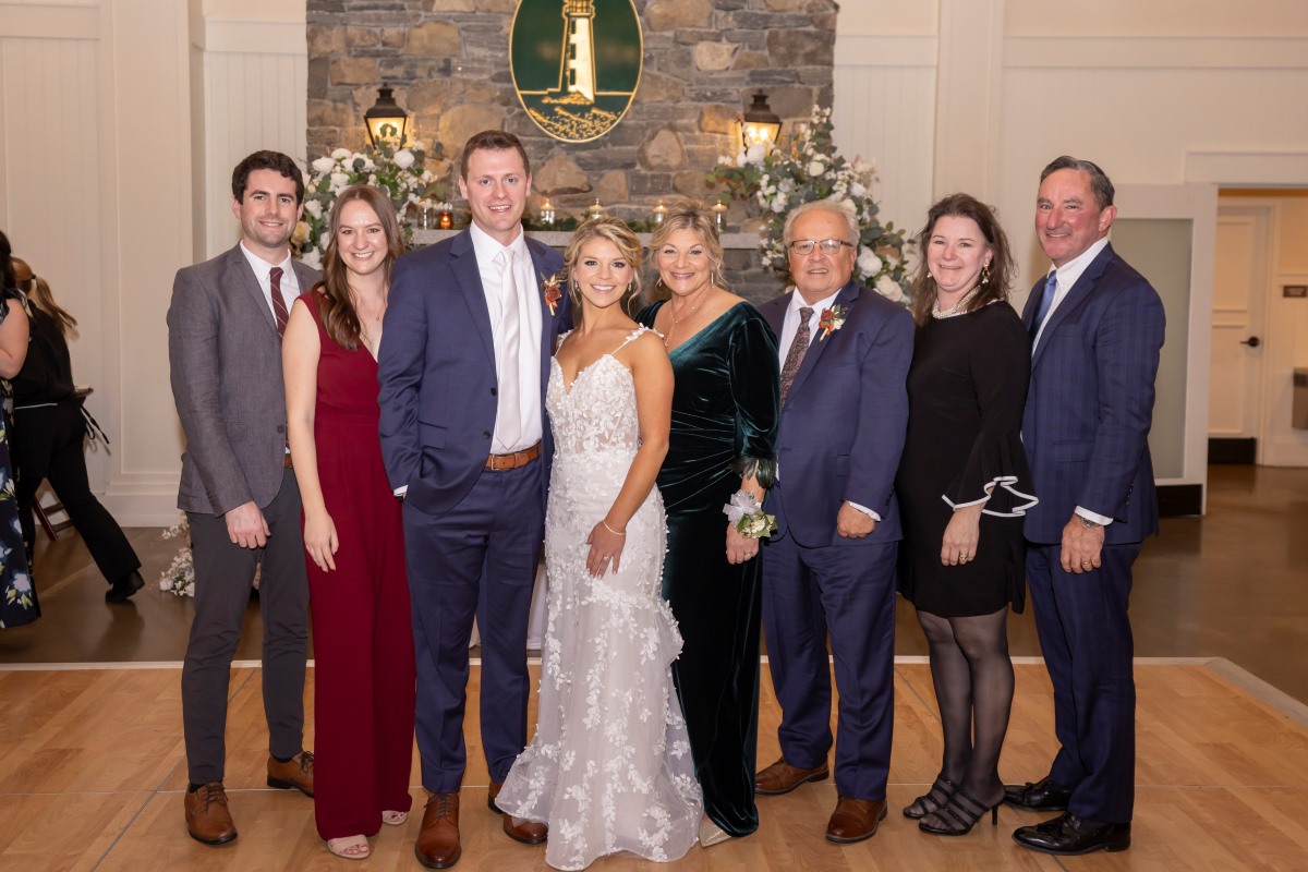 A luxury wedding party poses elegantly for a photo in front of a beautifully decorated fireplace.