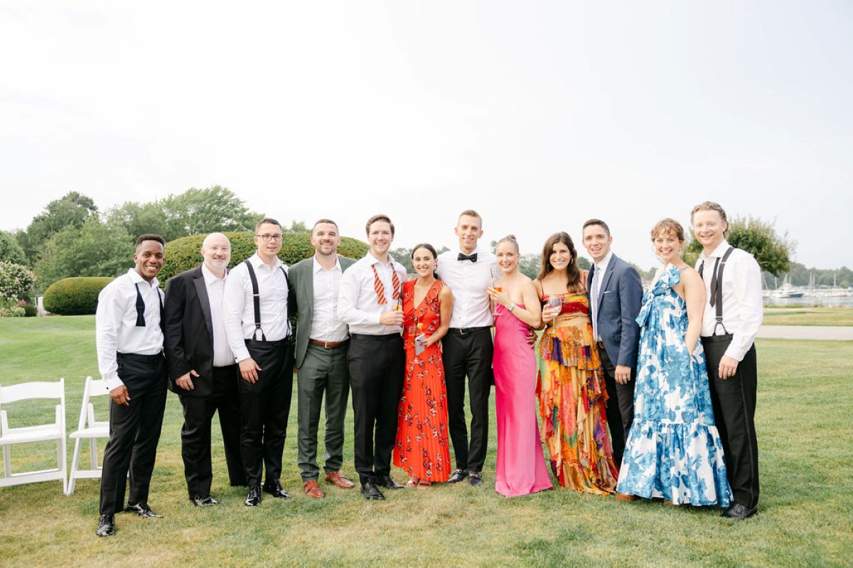 A group of elegantly dressed individuals posing together for a photo at a luxurious wedding celebration.