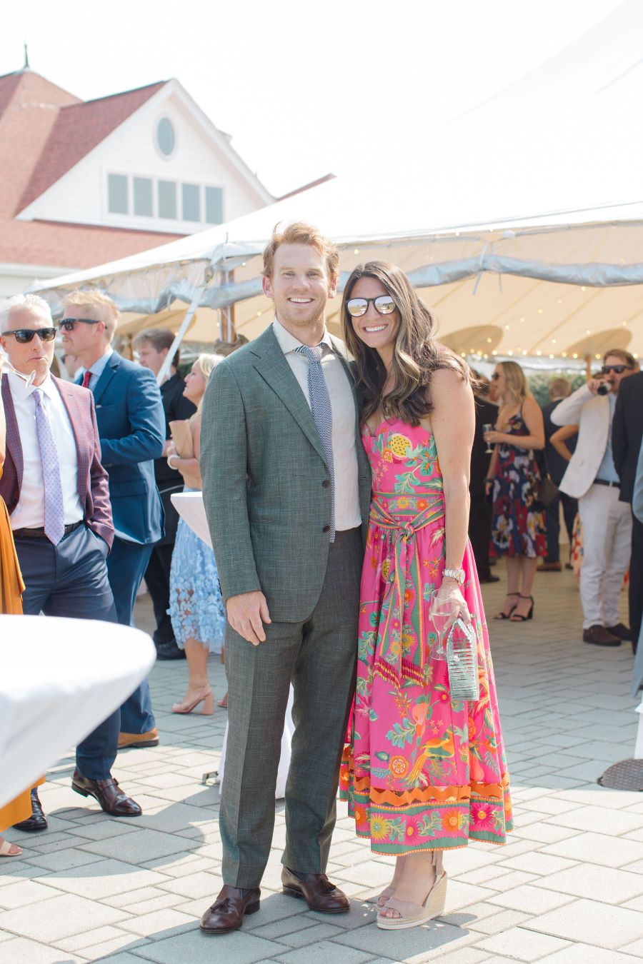 A couple elegantly posing for a photo at a luxurious outdoor wedding event, surrounded by beautiful decorations.