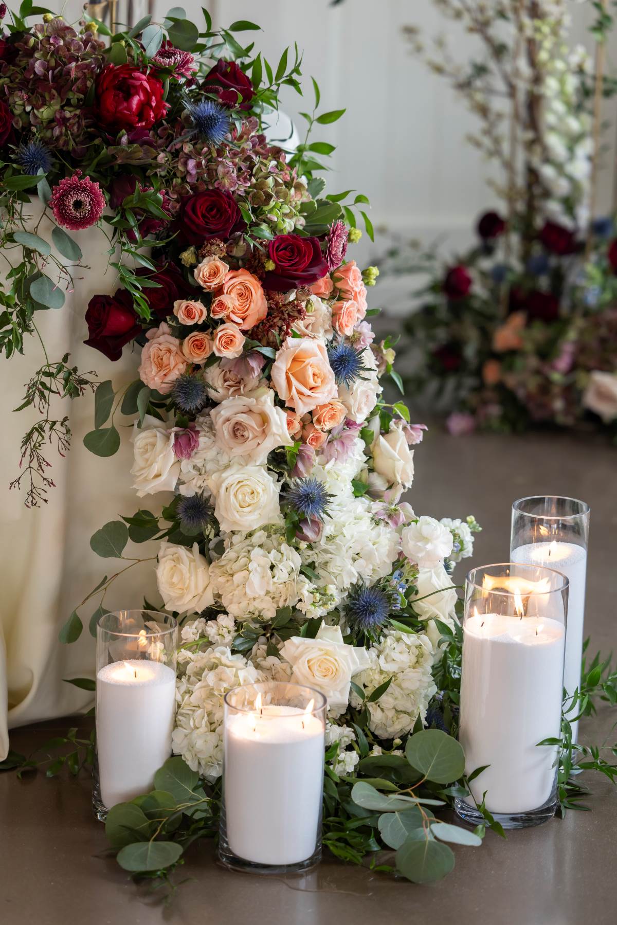 A beautifully arranged table featuring an assortment of flowers and lit candles, creating a warm and inviting atmosphere.