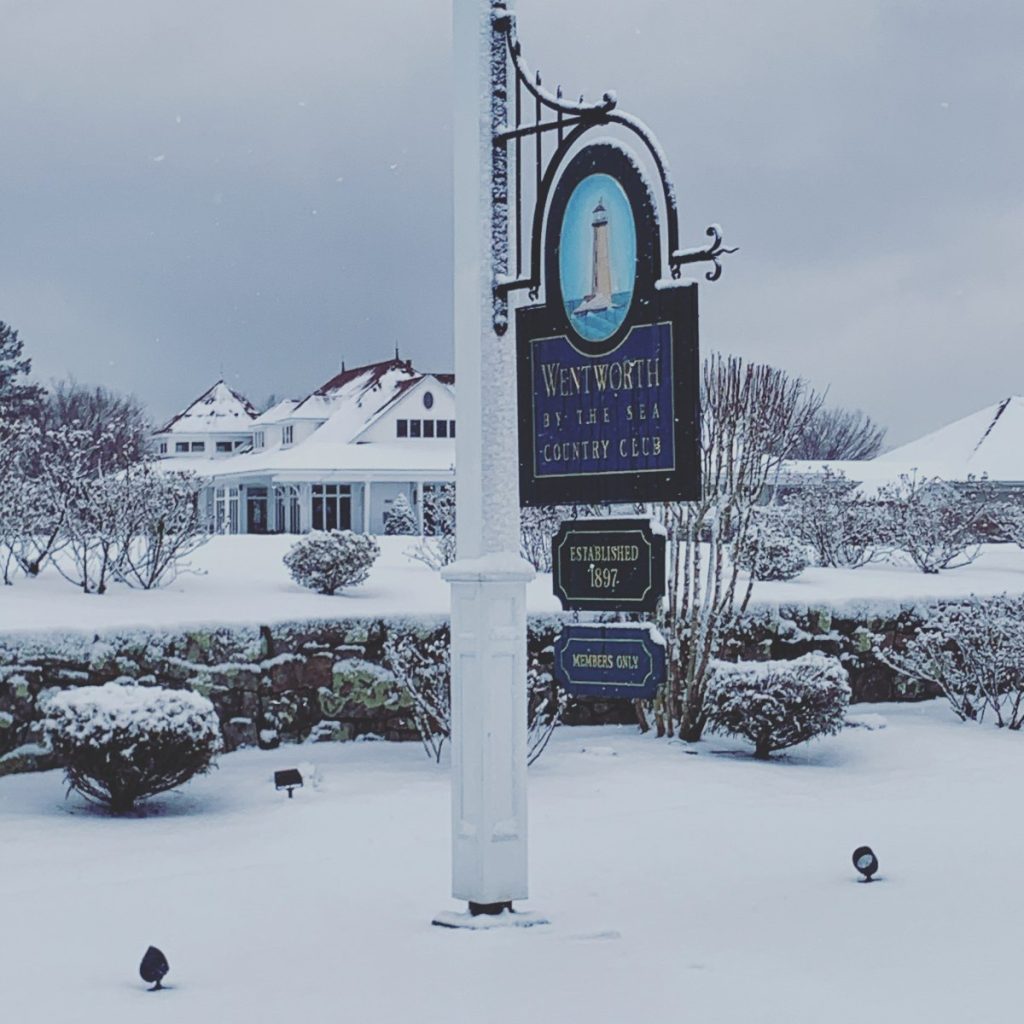 A snow-covered sign on a pole, elegantly marking the entrance to a luxurious wedding venue.