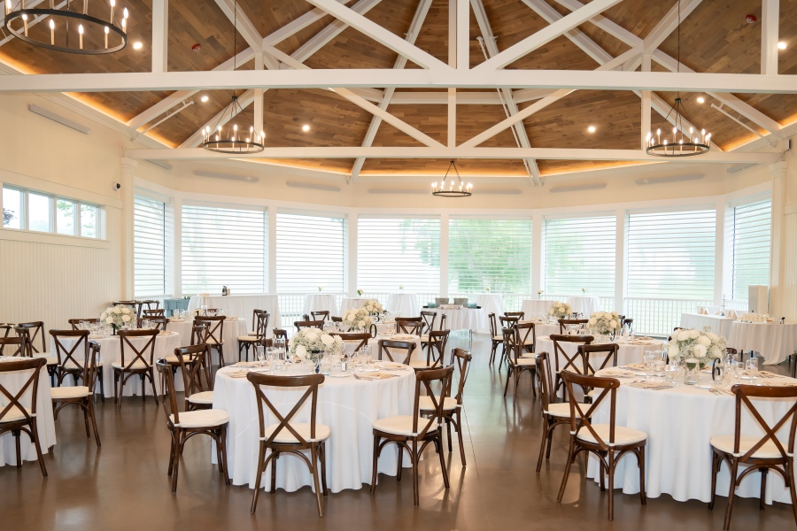 A grand dining room with a stone fireplace, beautifully arranged for a luxurious wedding reception.