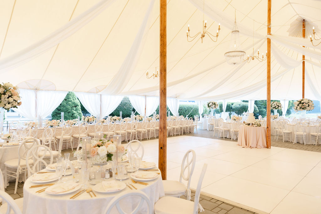 Wedding table settings beneath large outdoor tent